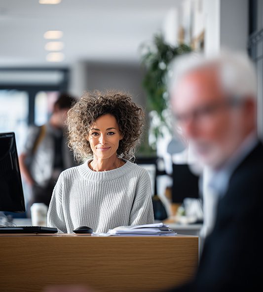 Femme souriante assise à son bureau dans un espace de travail moderne.